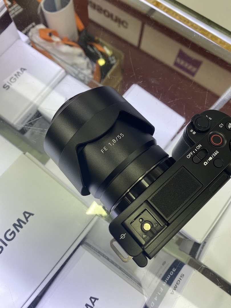 A close-up of a camera with a lens on display, surrounded by Sigma product boxes.