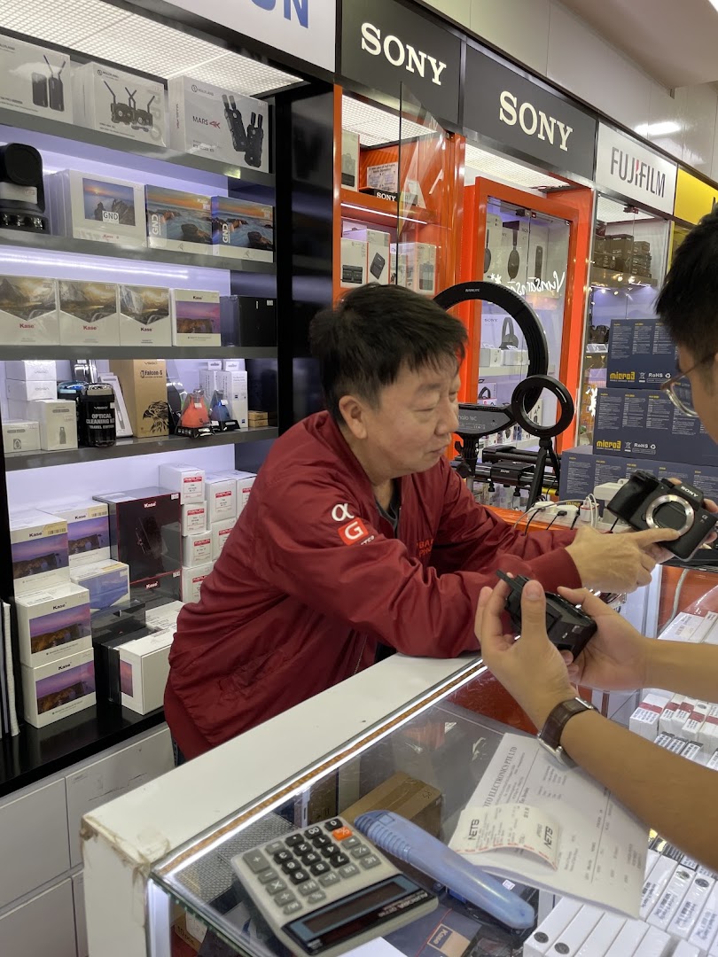 A customer interacts with staff at Bally Photo Electronics, showcasing cameras and accessories.