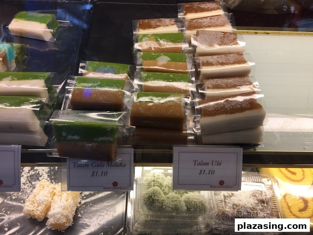 A vibrant display of traditional Indonesian and Peranakan kueh, including Talam Gula Melaka and Talam Ubi.