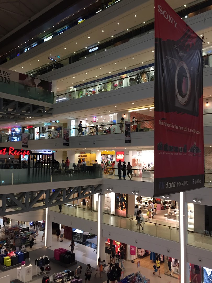 An expansive view of a multi-level shopping mall interior with various retail stores and shoppers.