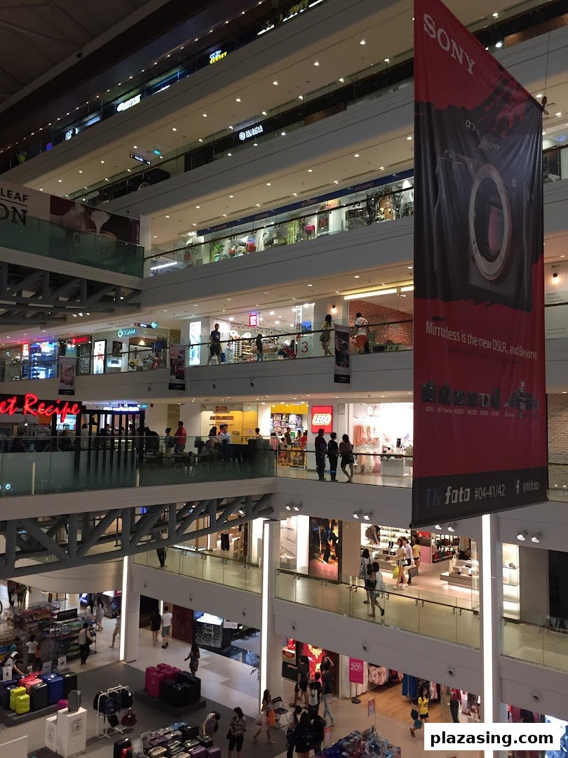 An expansive view of a multi-level shopping mall interior with various retail stores and shoppers.