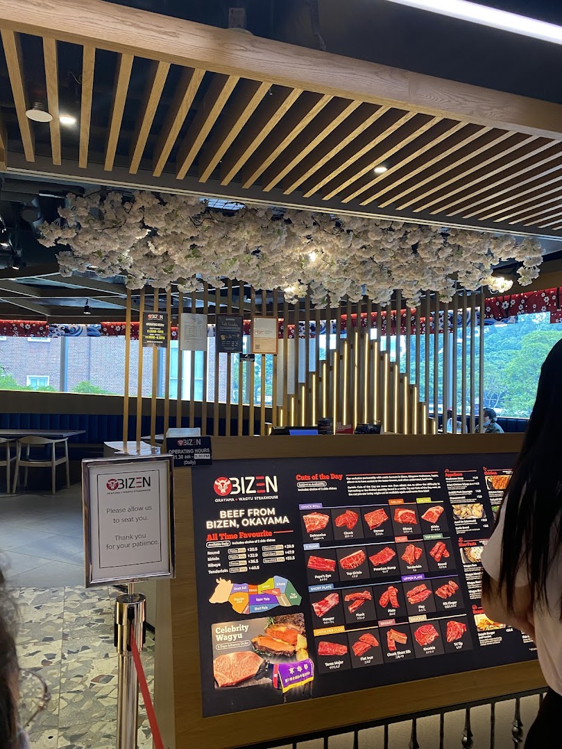 Interior view of Bizen Wagyu Steakhouse featuring a large display of beef cuts and a waiting area.