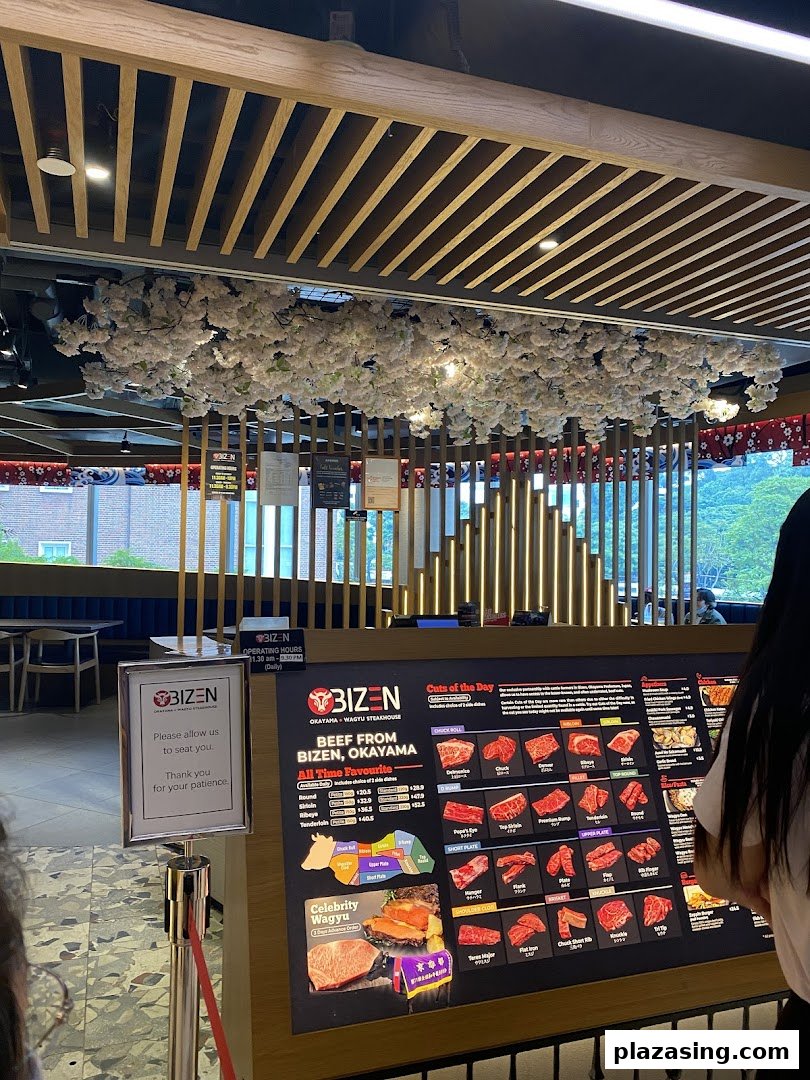 Interior view of Bizen Wagyu Steakhouse featuring a large display of beef cuts and a waiting area.