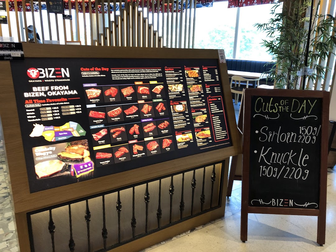A large digital menu board showcasing wagyu beef cuts and prices, accompanied by a chalkboard with daily specials.