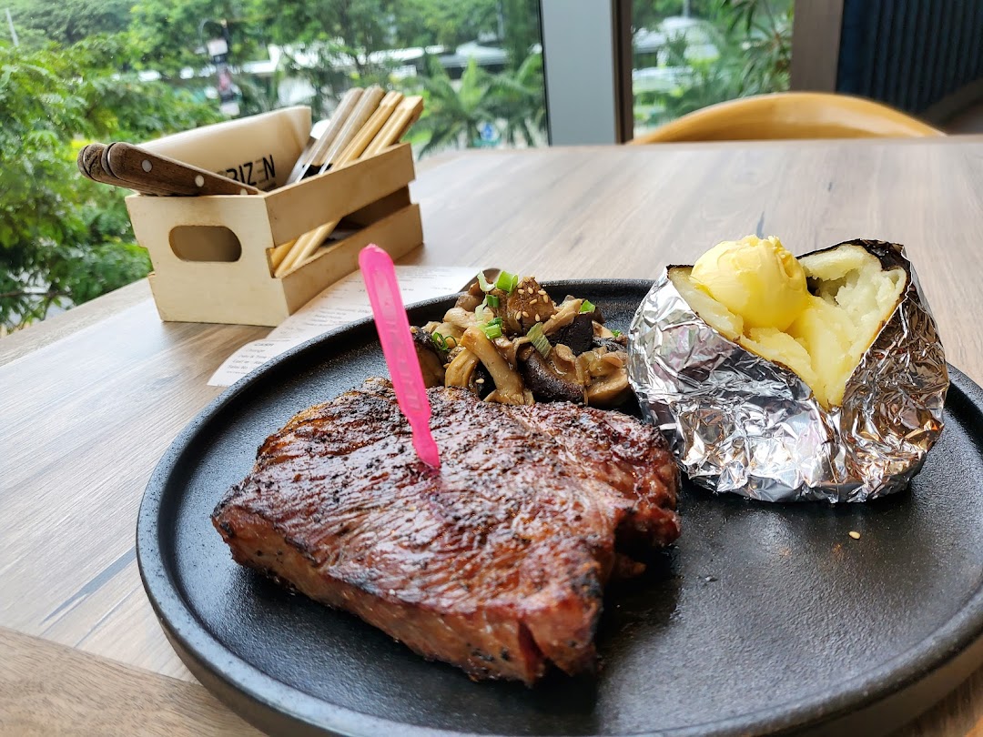 A perfectly grilled steak served with a baked potato and sautéed mushrooms on a black plate.