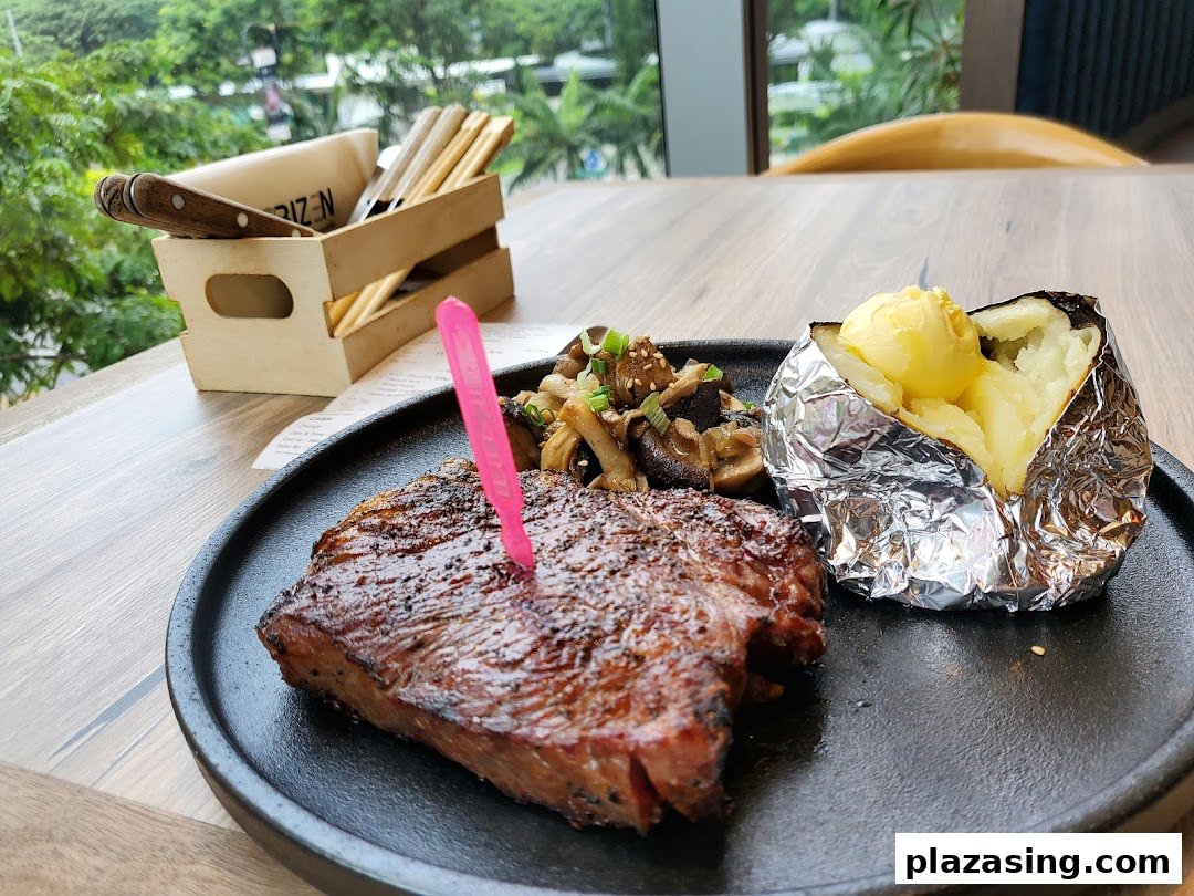 A perfectly grilled steak served with a baked potato and sautéed mushrooms on a black plate.