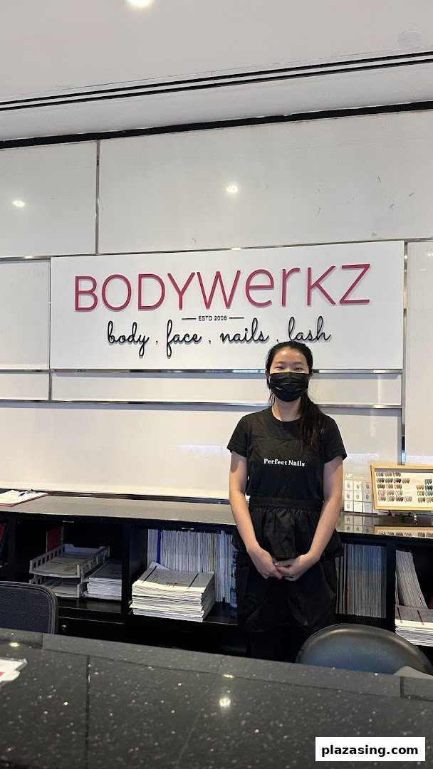 A friendly staff member stands at the reception desk of BodyWerkz, a beauty salon.