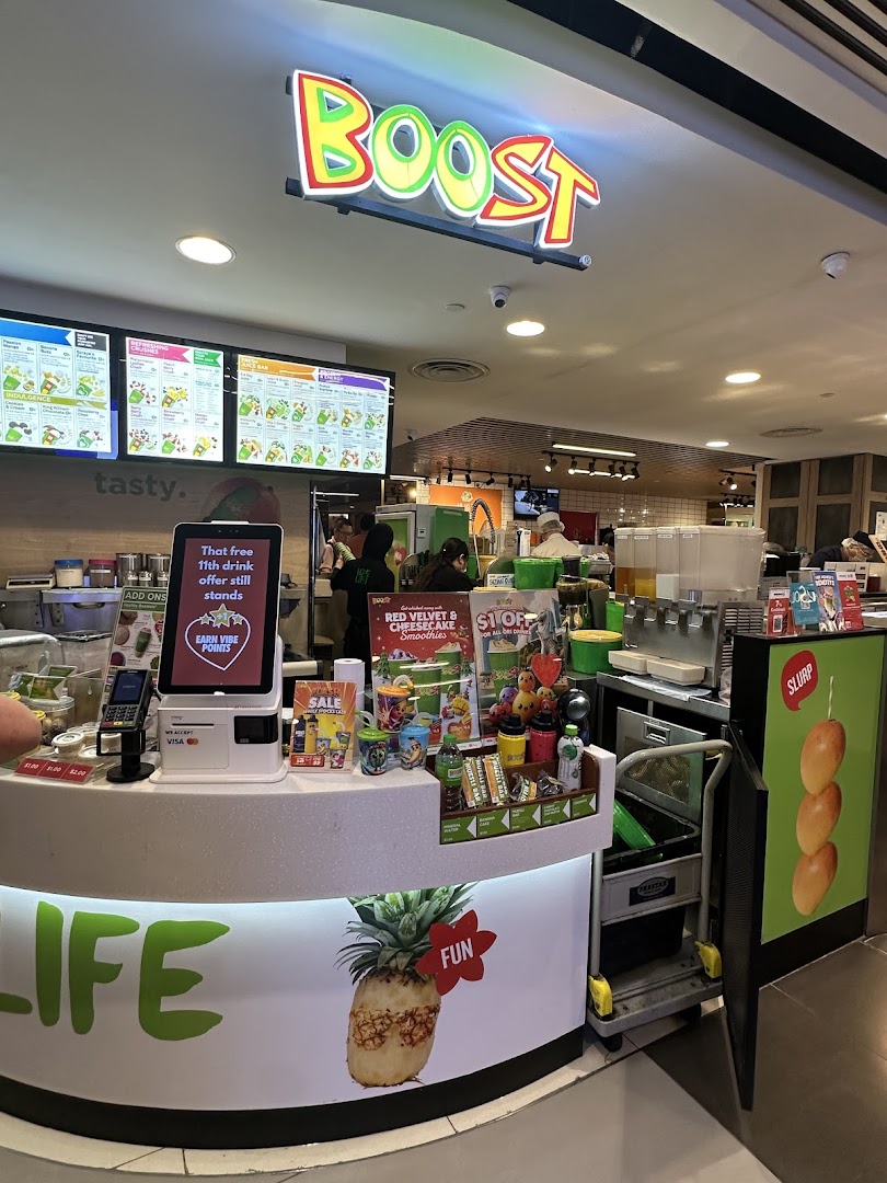 An interior view of Boost Juice at Plaza Singapura, featuring the vibrant counter and digital menu boards.