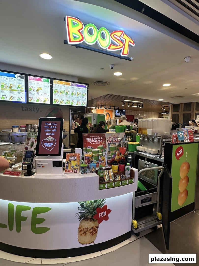 An interior view of Boost Juice at Plaza Singapura, featuring the vibrant counter and digital menu boards.