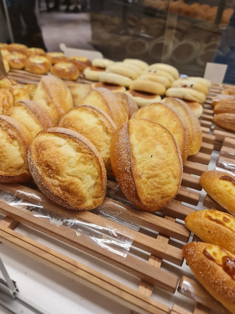 A close-up of various freshly baked breads and pastries displayed on wooden racks at BreadTalk.