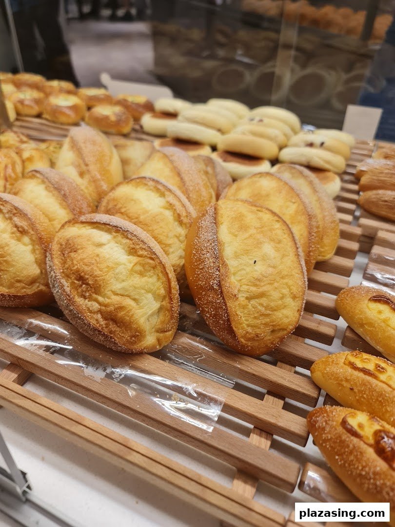 A close-up of various freshly baked breads and pastries displayed on wooden racks at BreadTalk.