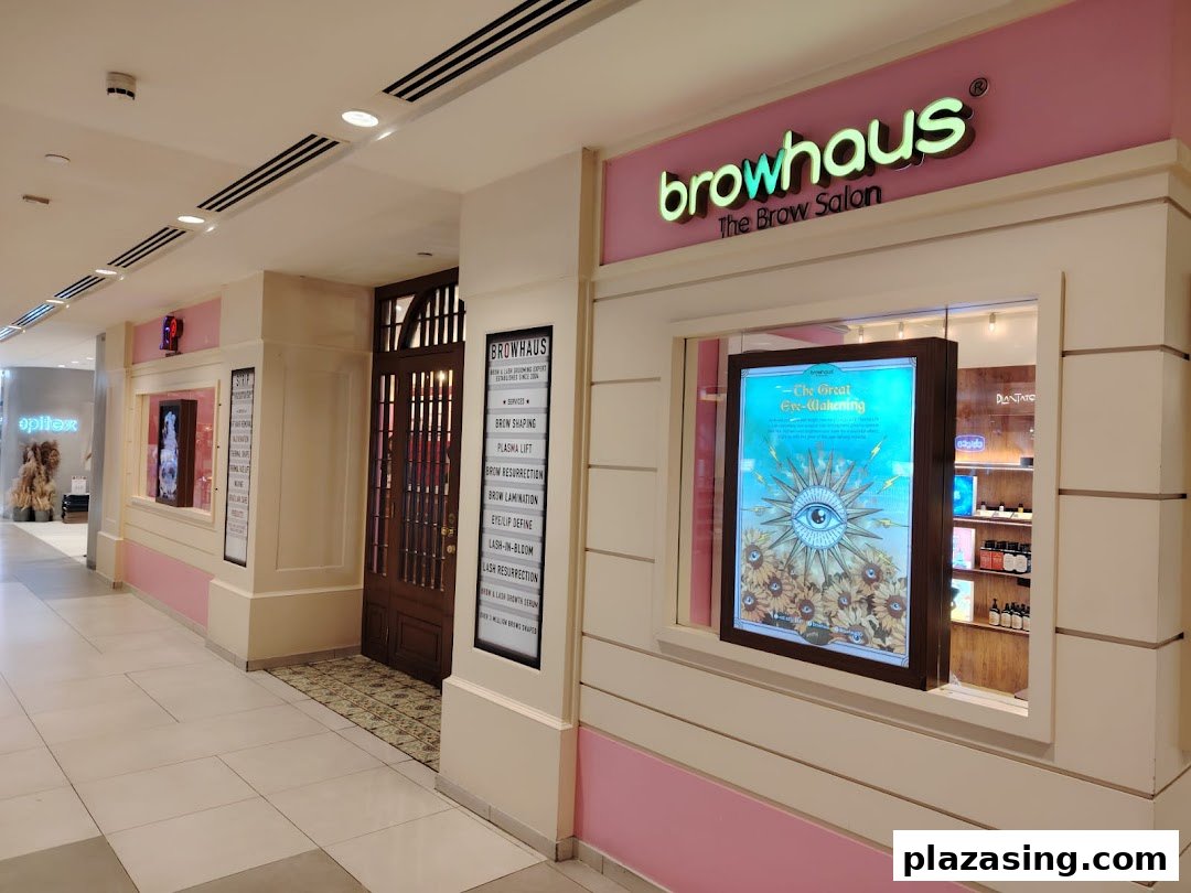 The inviting pink and white shopfront of Browhaus, 'The Brow Salon,' featuring its entrance and a promotional display.
