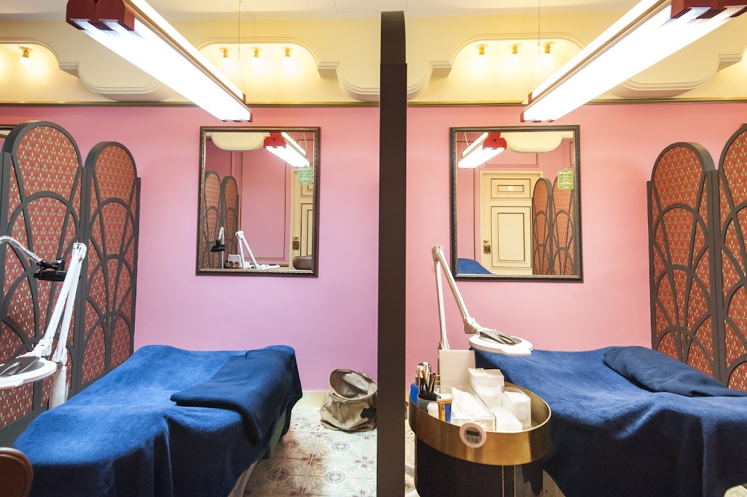 Two vibrant pink treatment rooms with blue beds, ornate screens, and beauty equipment at Browhaus.
