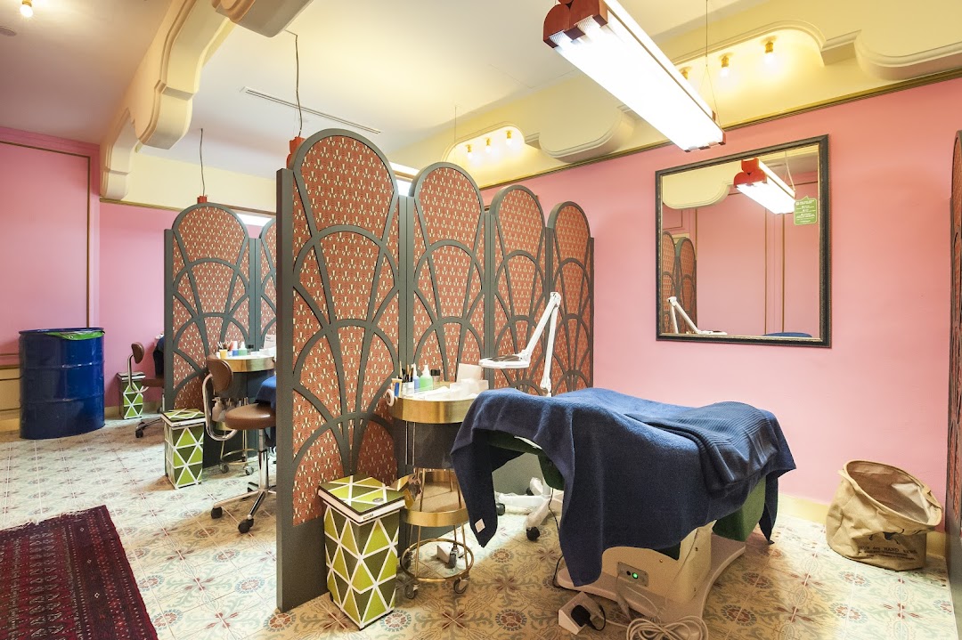 Interior view of Browhaus, featuring pink walls, decorative screens, and multiple beauty treatment stations.