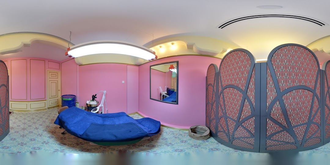 A vibrant pink and gold treatment room with a blue bed and decorative screens at Browhaus.