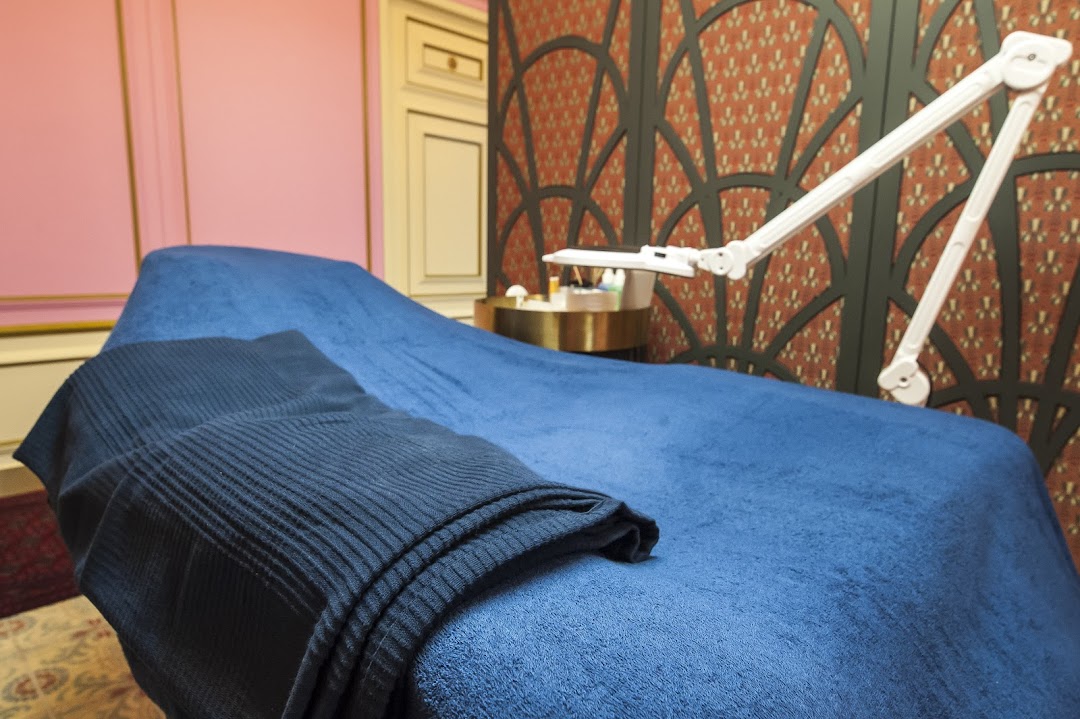 A comfortable treatment bed with blue covers and a magnifying lamp in a stylish beauty room.
