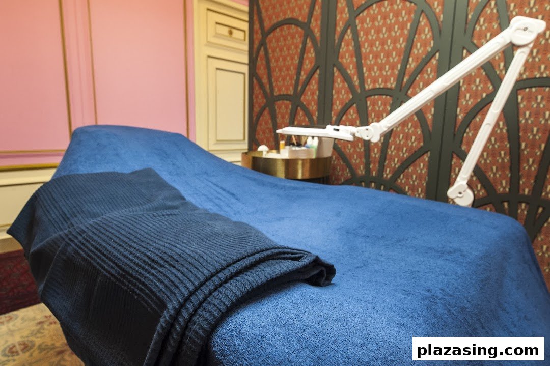 A comfortable treatment bed with blue covers and a magnifying lamp in a stylish beauty room.