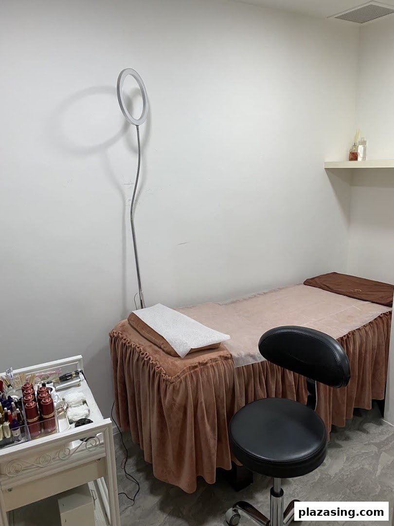 A clean and well-equipped treatment room for eyebrow embroidery services, featuring a bed, stool, and supplies.