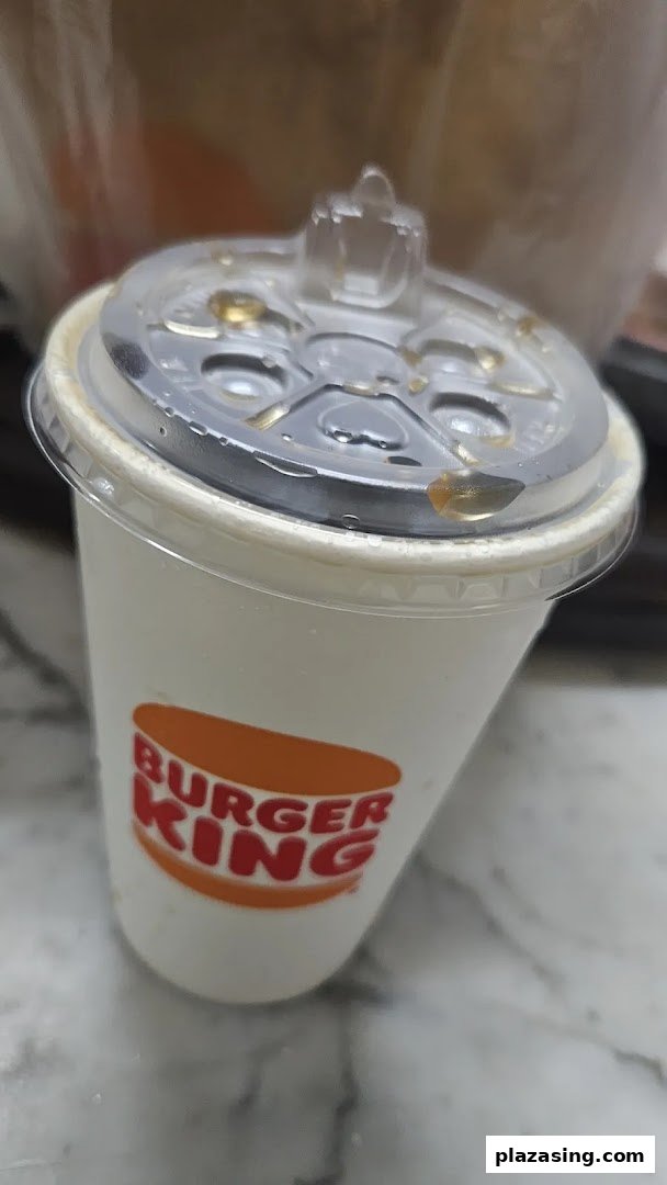 A Burger King branded drink cup with a clear lid, showing condensation.