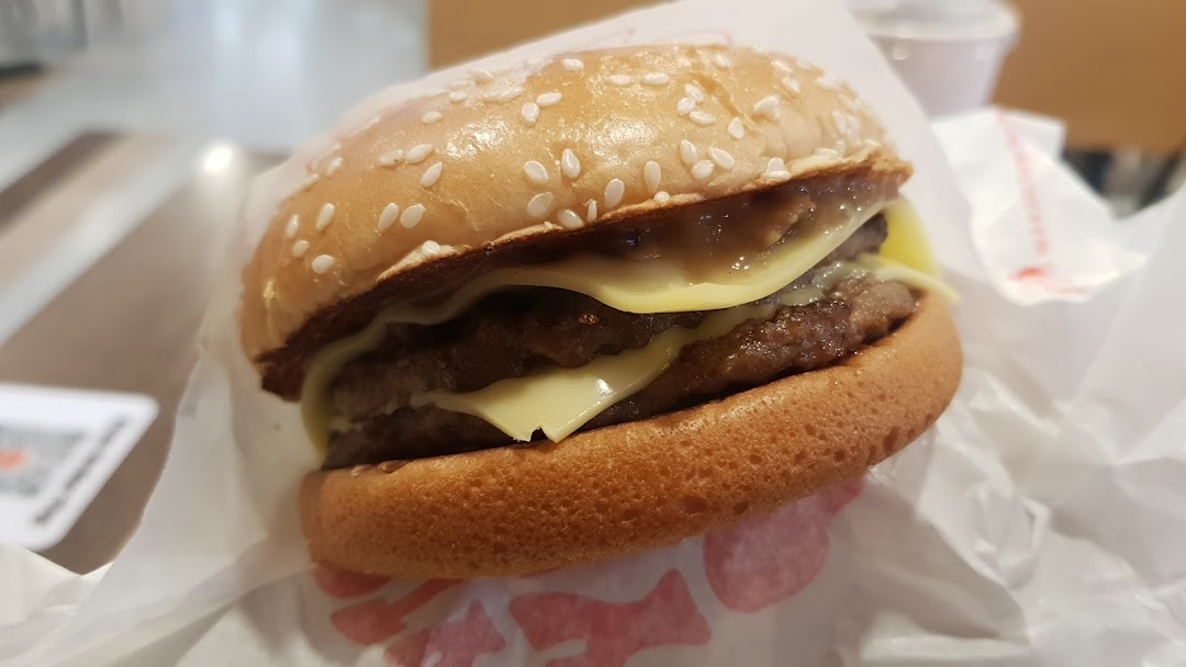 A close-up of a double cheeseburger with melted cheese and a sesame seed bun.