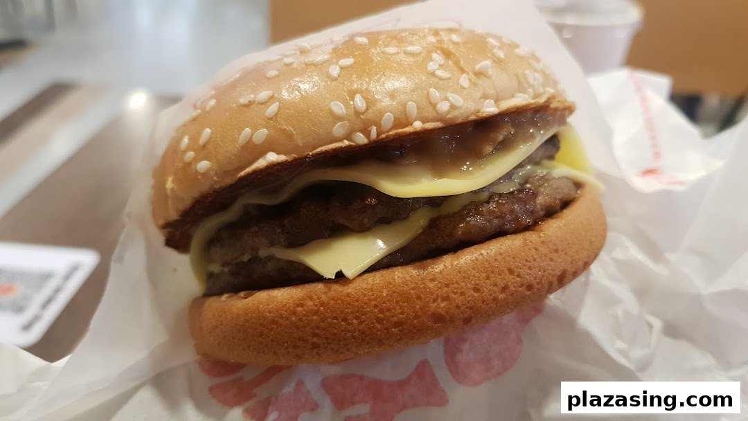 A close-up of a double cheeseburger with melted cheese and a sesame seed bun.