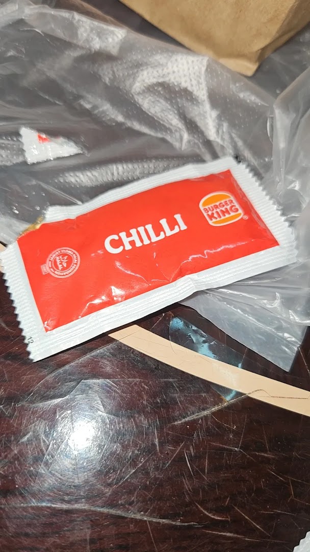A Burger King chilli sauce packet on a table, ready for a meal.