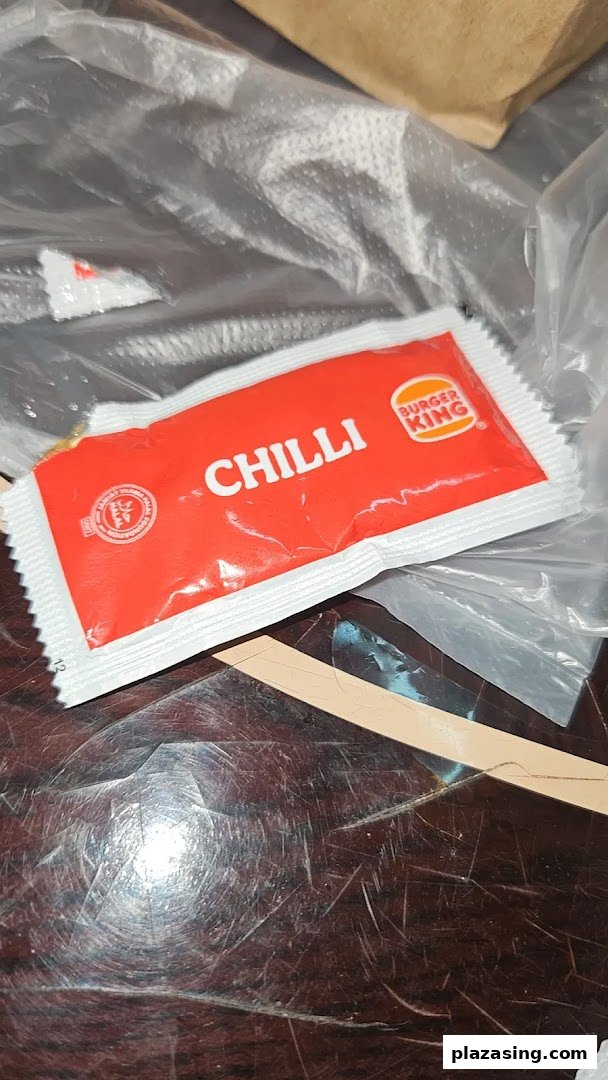 A Burger King chilli sauce packet on a table, ready for a meal.