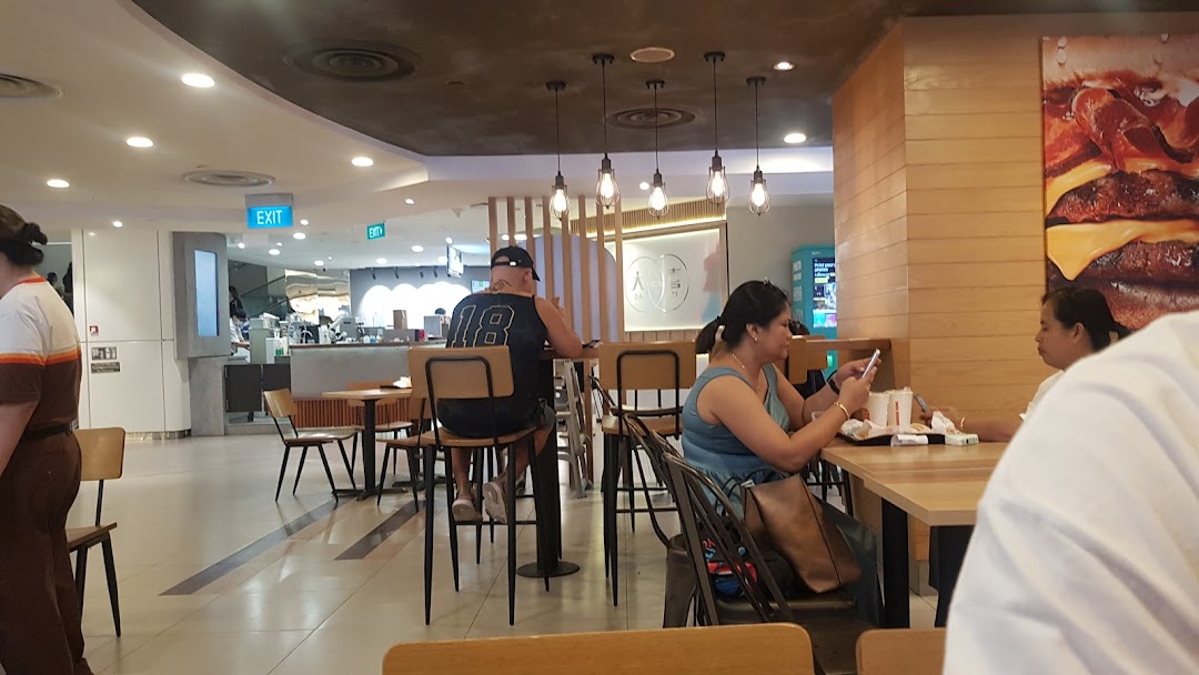 Customers enjoying meals inside Burger King, featuring a large burger graphic and modern decor.