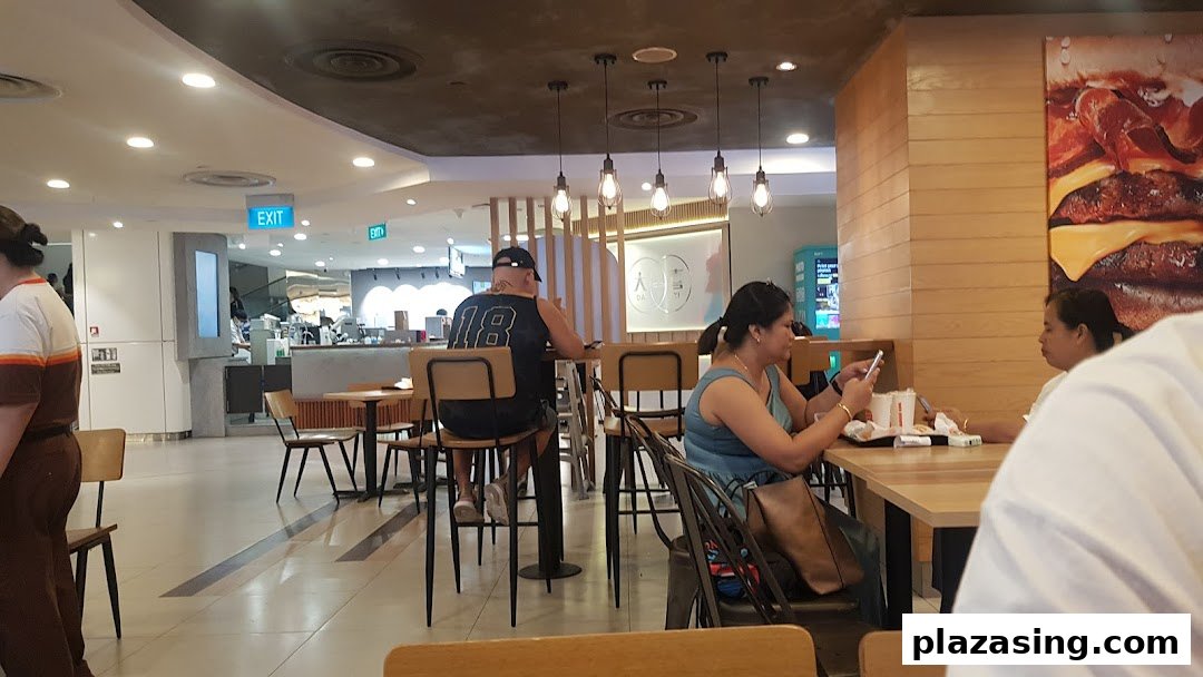Customers enjoying meals inside Burger King, featuring a large burger graphic and modern decor.