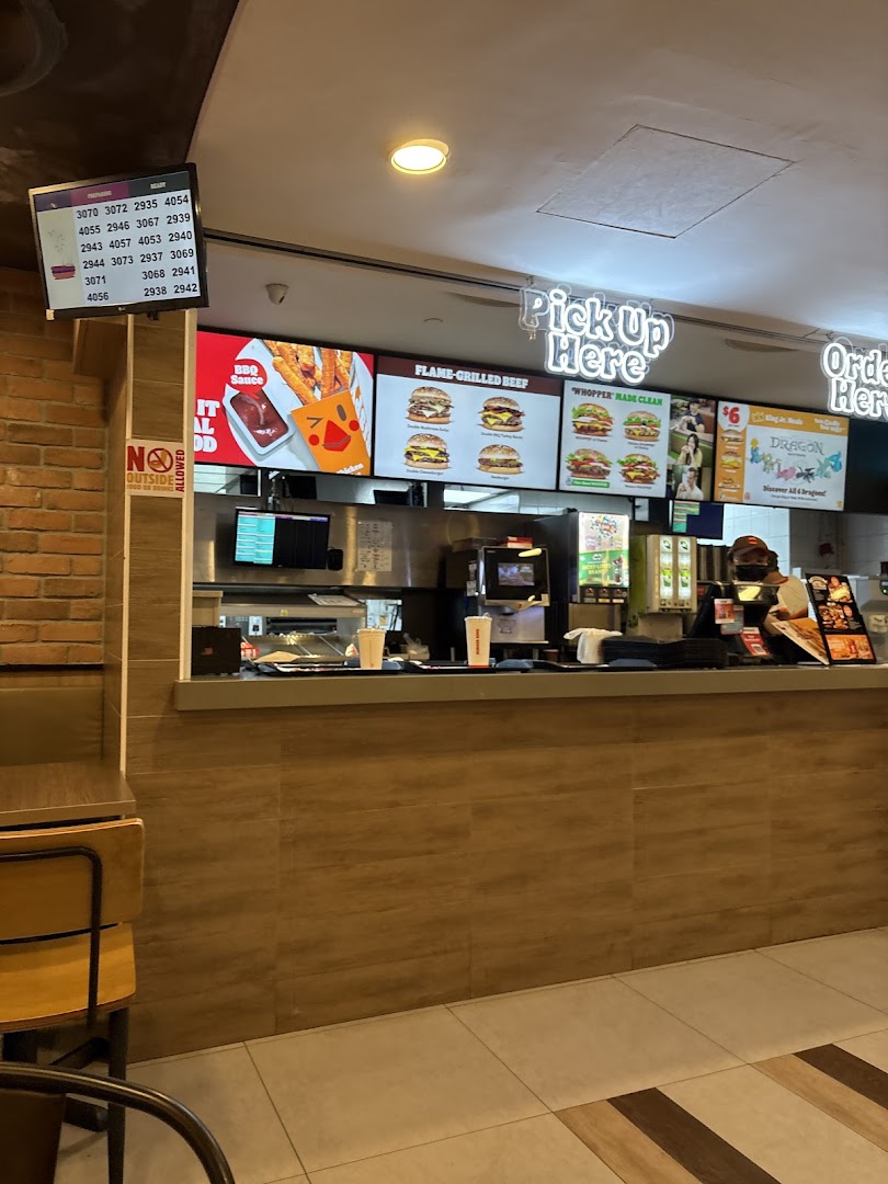 Interior view of Burger King's service counter with digital menu boards and an order pickup screen.
