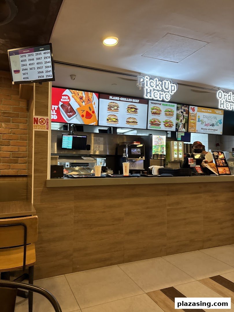 Interior view of Burger King's service counter with digital menu boards and an order pickup screen.