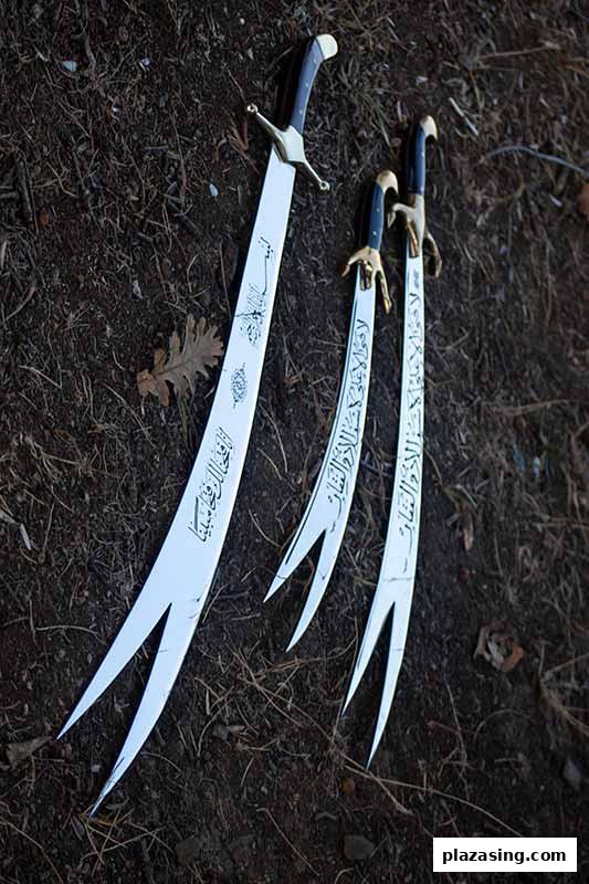 Three ornate swords with Arabic calligraphy and unique split blades lie on dark ground.