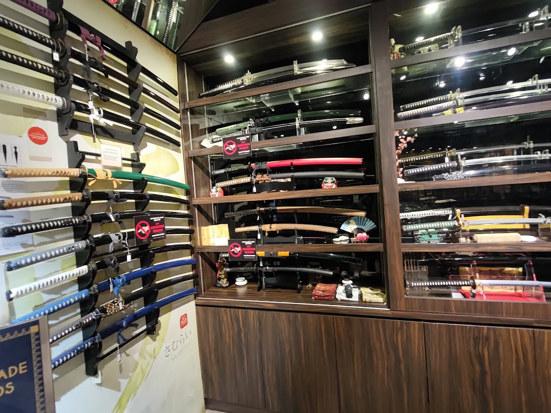 A shop interior showcasing a diverse collection of swords, including katanas, displayed on walls and in glass cases.
