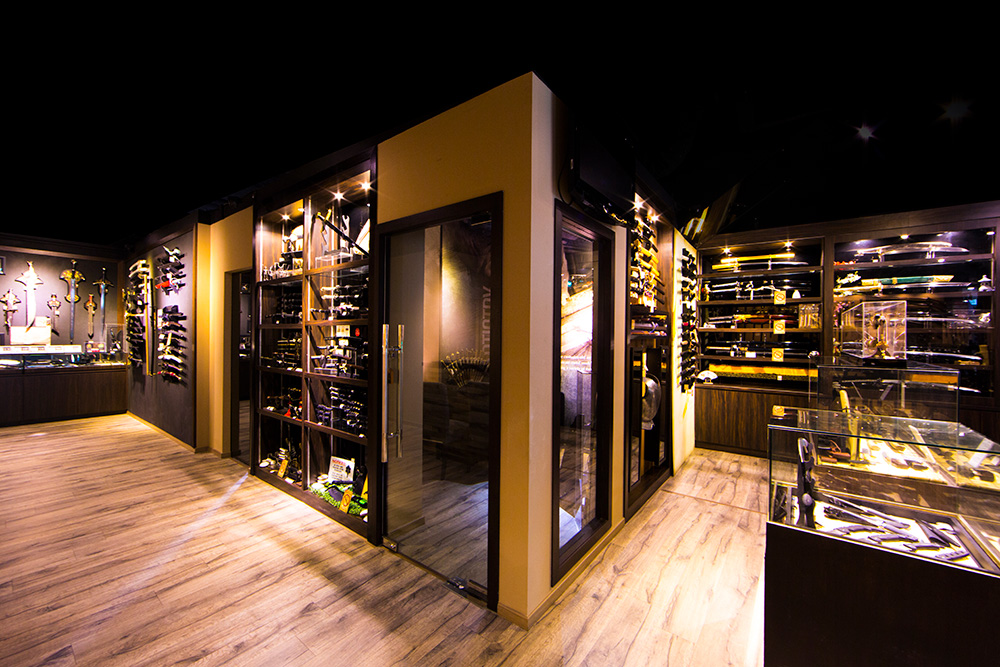 An interior view of CAESARS Swords.Guns.Armour, showcasing a wide array of swords, knives, and collectibles in display cases.