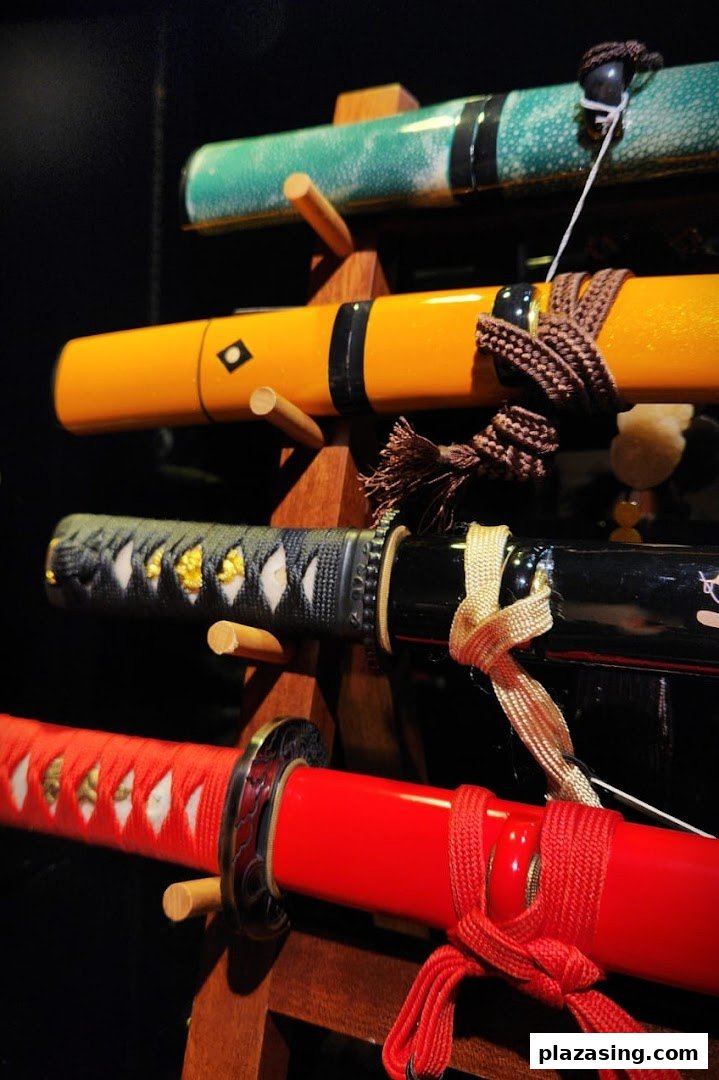Close-up of several colorful decorative swords displayed on a wooden stand.