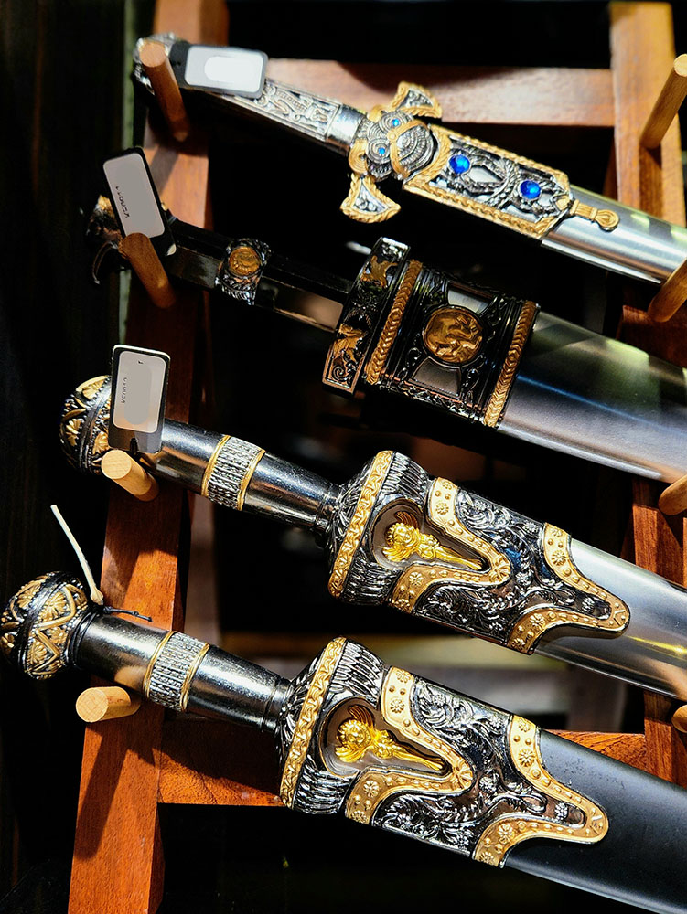 Close-up of ornate, decorative swords and daggers displayed on a wooden rack.