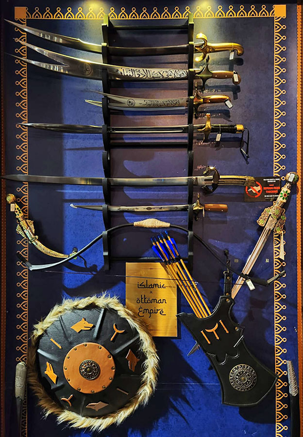A display of historical swords, a bow and arrows, and a shield, showcasing Ottoman Empire themed weaponry.