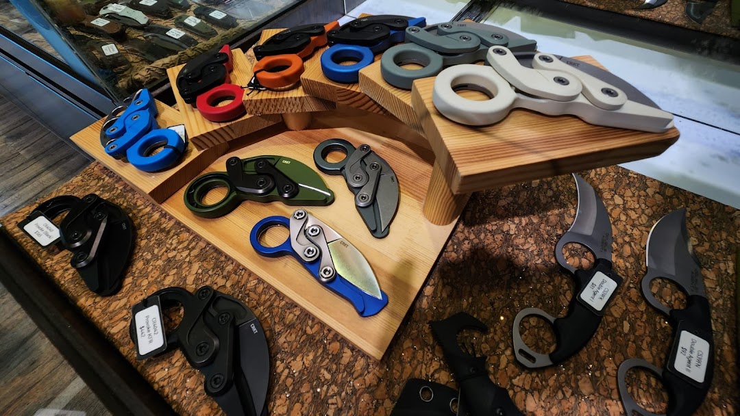 A display of various tactical and folding knives, including karambits, in different colors and designs.