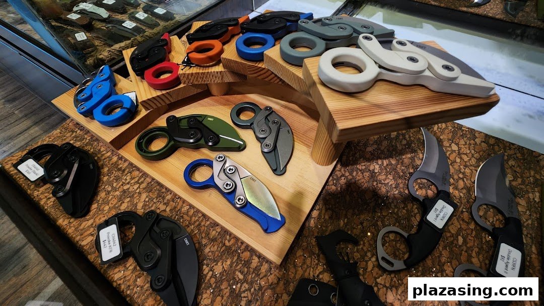 A display of various tactical and folding knives, including karambits, in different colors and designs.