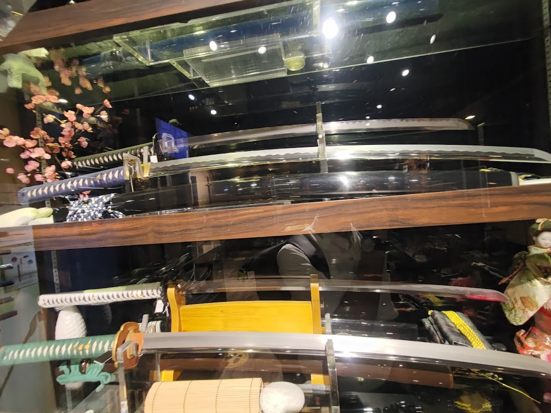 A display case showcasing an array of intricately designed swords, including katanas, with traditional Japanese decor.