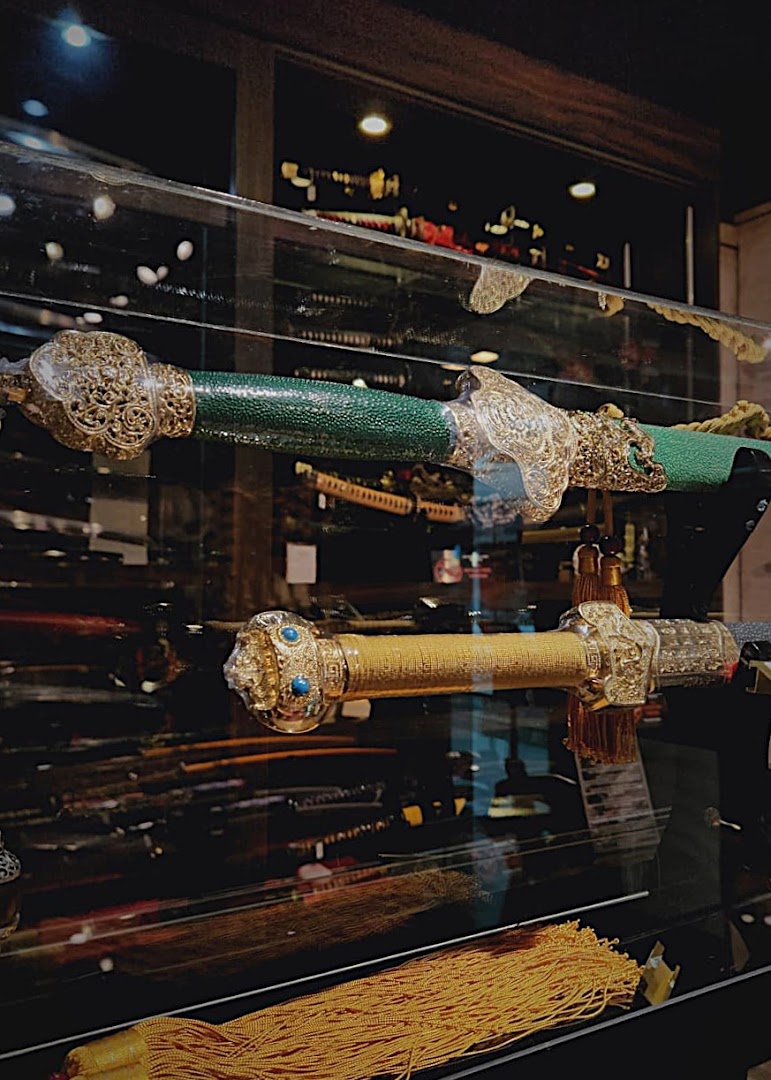 Two ornate swords with decorative hilts and scabbards displayed in a glass case.