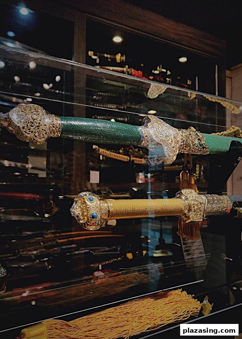 Two ornate swords with decorative hilts and scabbards displayed in a glass case.