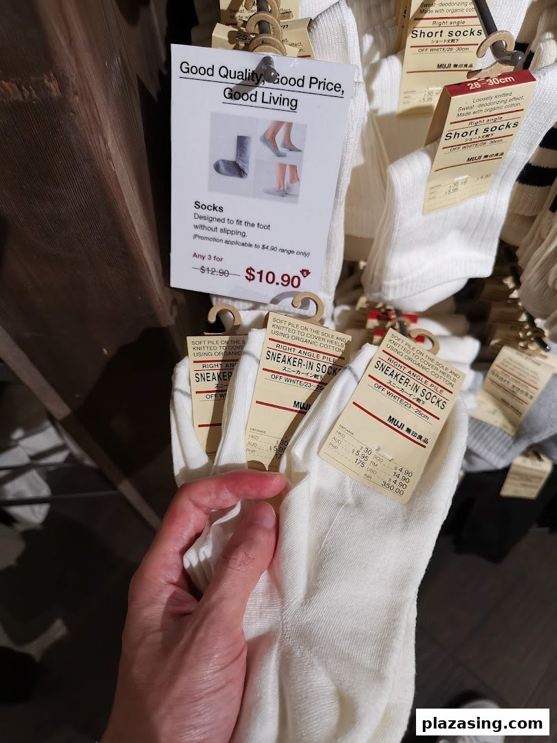 A hand holds white socks from a display, showing product tags and a promotional offer.