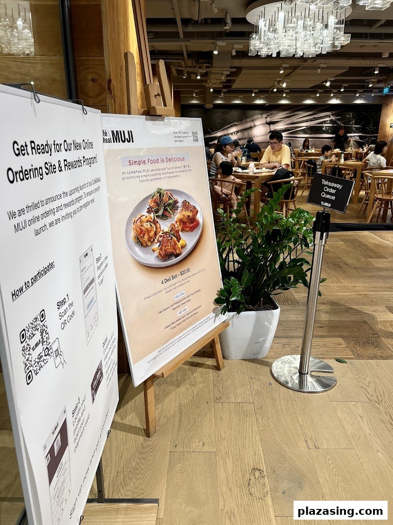 Interior view of CafèMeal MUJI with diners, featuring promotional signs for online ordering and deli sets.