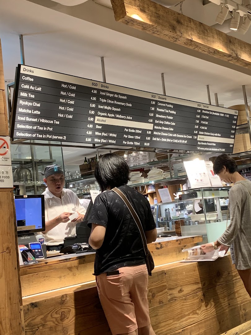 A customer orders at the counter of CafèMeal, with a detailed menu board displaying drinks, desserts, and deli sets.