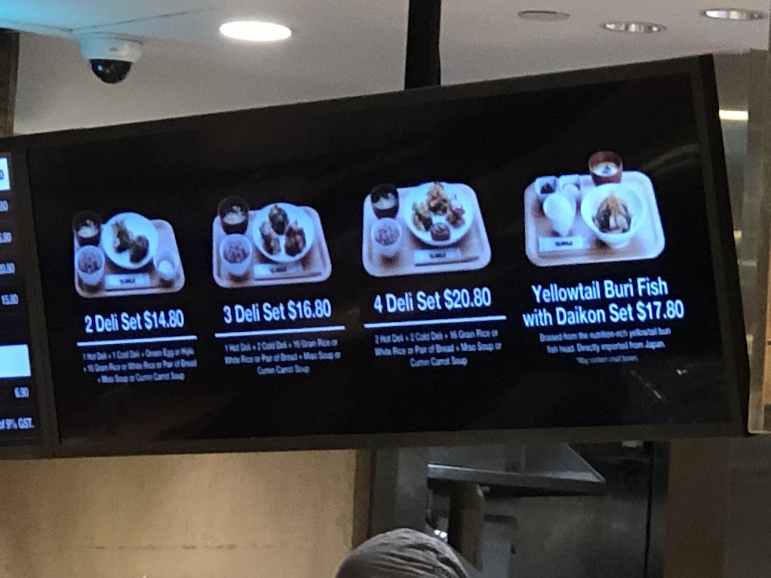 A digital menu board displaying various Japanese deli sets and a Yellowtail Buri Fish dish with prices.