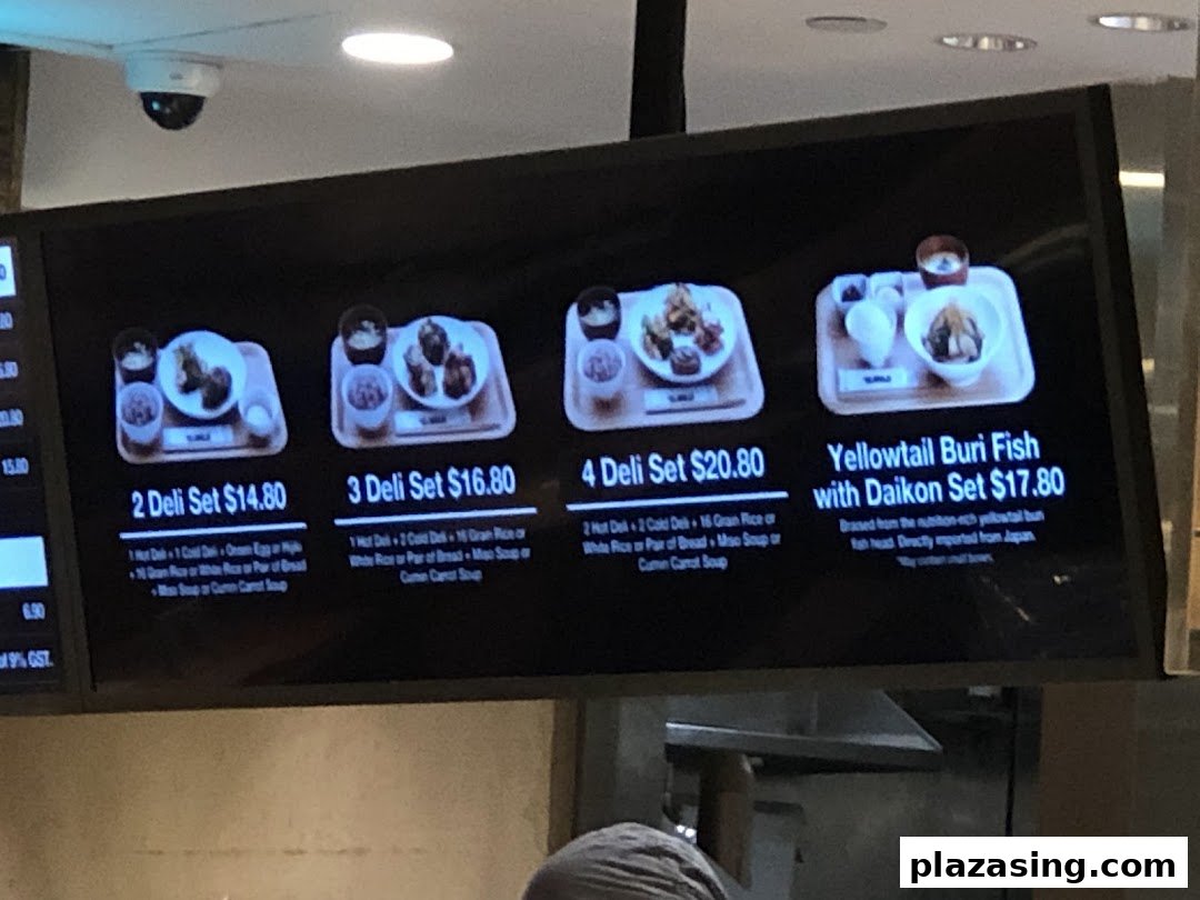 A digital menu board displaying various Japanese deli sets and a Yellowtail Buri Fish dish with prices.