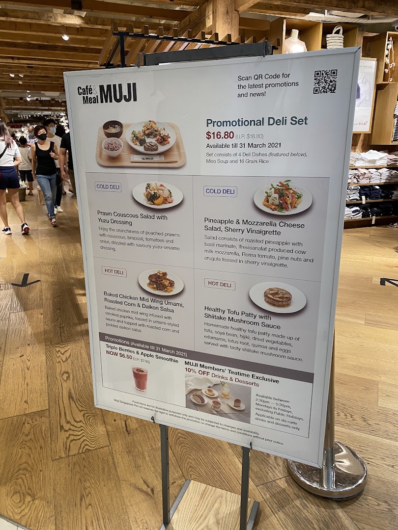 A promotional menu board for CafèMeal MUJI, showcasing deli sets, salads, and drinks.