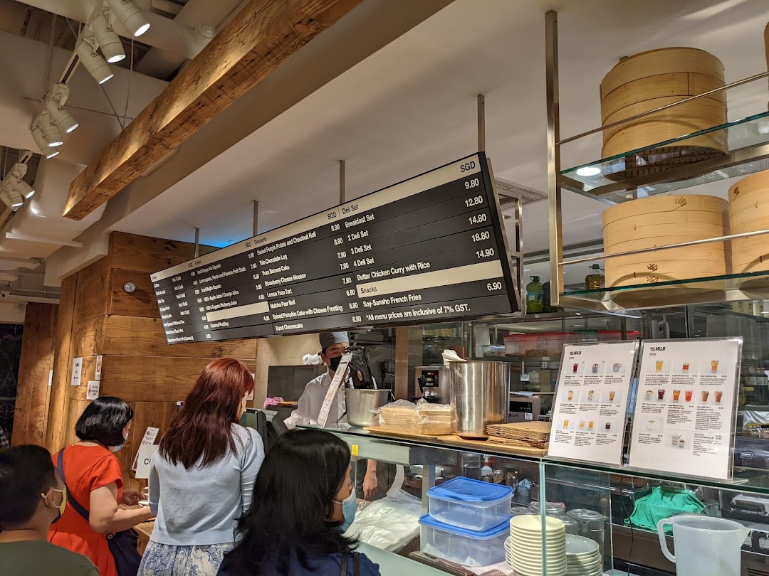 Customers queue at the counter of CafèMeal, featuring a large overhead menu board and display cases.