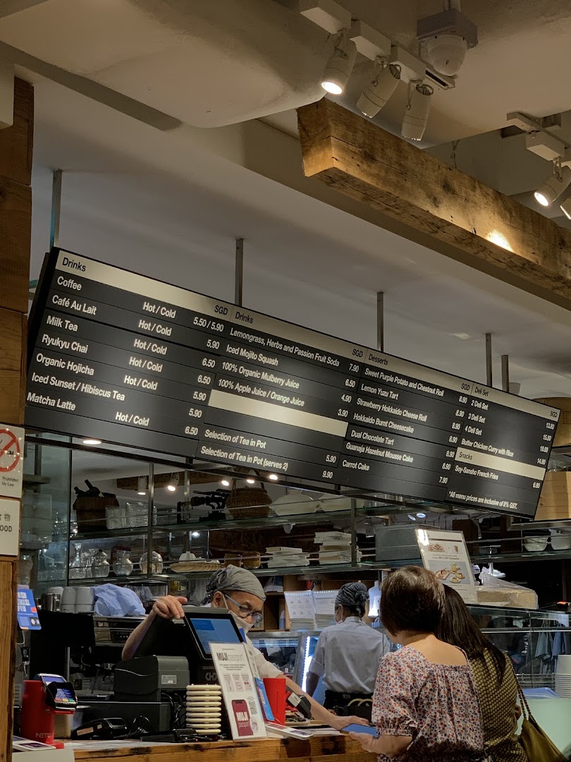 Overhead menu board displaying drinks, desserts, and deli sets at a cafe counter with customers.